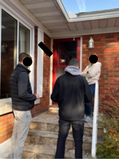 2 students talking to someone on their front porch.
